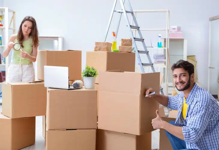 Two young people taping moving boxes